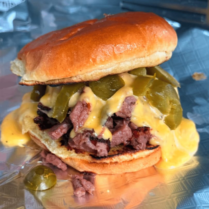 Duffy's BBQ and Grill's cheesesteak sandwich with melted cheese and pickled jalapeños on foil.