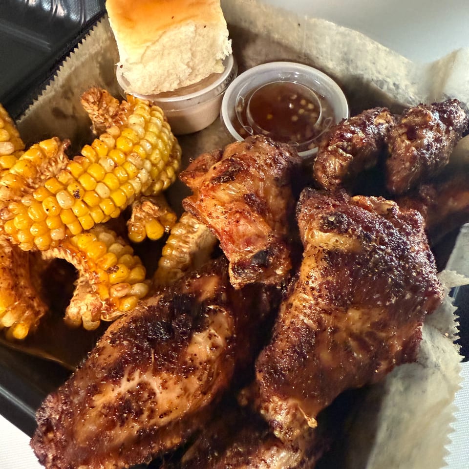 Duffy's BBQ chicken wings, corn on the cob, and a biscuit in a basket.