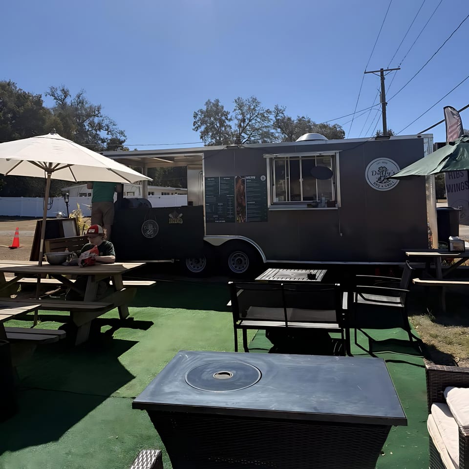 Duffy's BBQ and Grill food truck with outdoor seating, including picnic tables and lounge chairs.