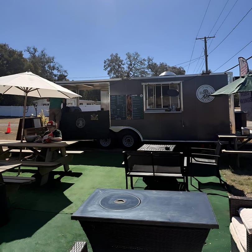 Duffy's BBQ and Grill food truck with outdoor seating, including picnic tables and lounge chairs.