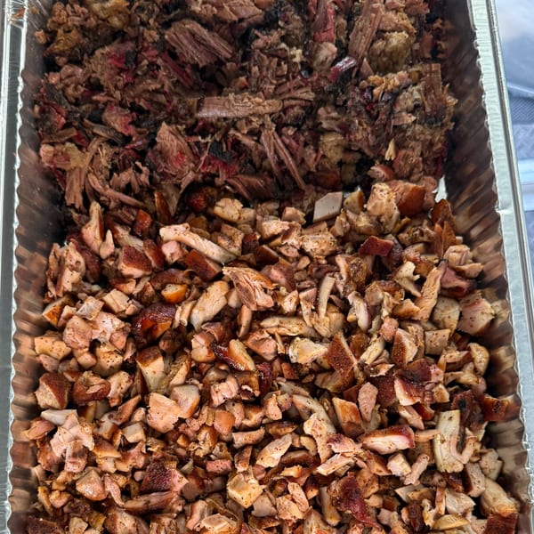 A catering tray filled with shredded BBQ brisket and diced BBQ chicken from Duffy's BBQ and Grill.