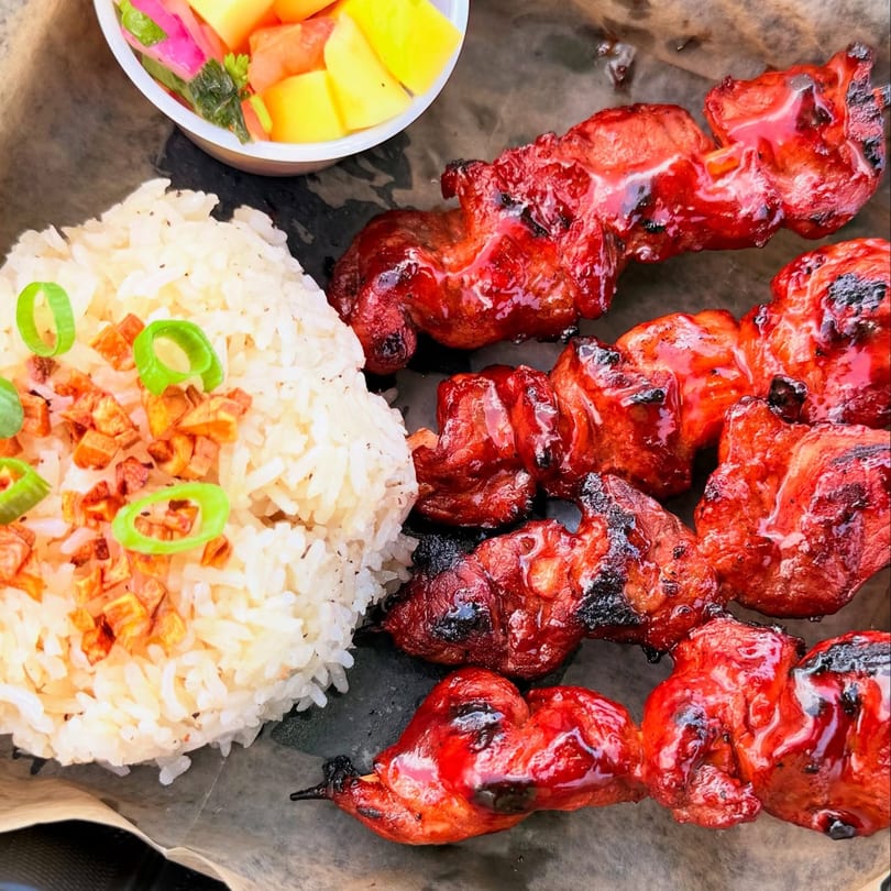 Duffy's BBQ and Grill's vibrant red BBQ chicken skewers with rice and fruit salad.