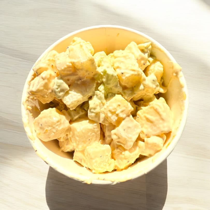 A bowl of creamy potato salad with visible black pepper, a classic side dish at Duffy's BBQ.